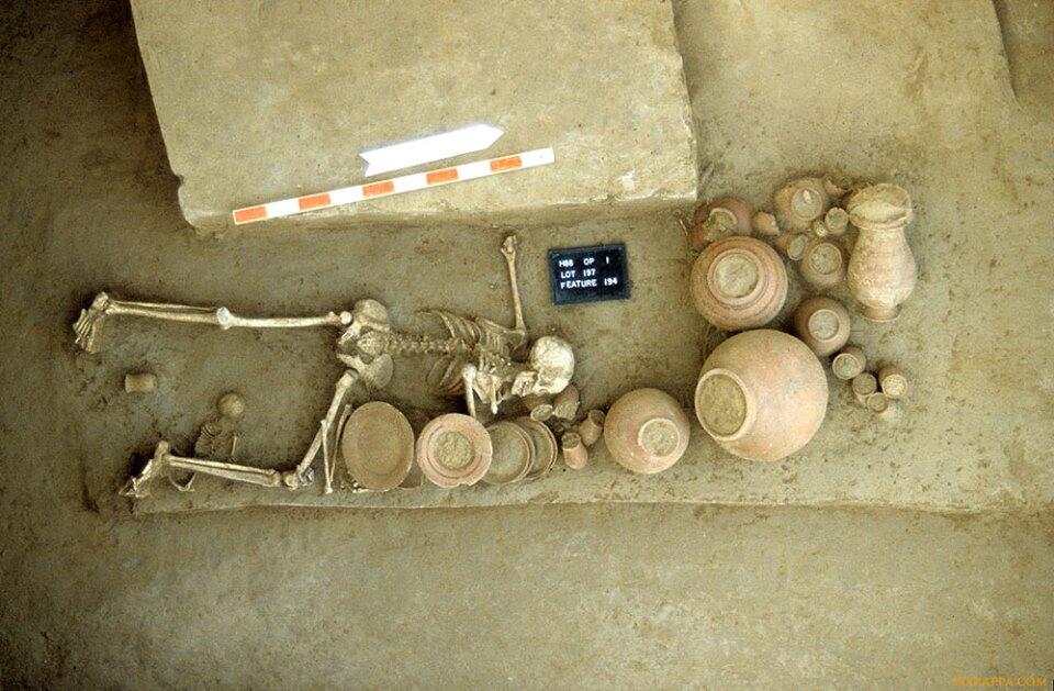 His burial was disturbed in antiquity, possibly by ancient Harappan grave robbers. Besides the fact that the body is flipped and the pottery disturbed, the left arm of the woman is broken and shell bangles that would normally be found on the left arm are missing. The infant was buried in a small pit beneath the legs of the mother.