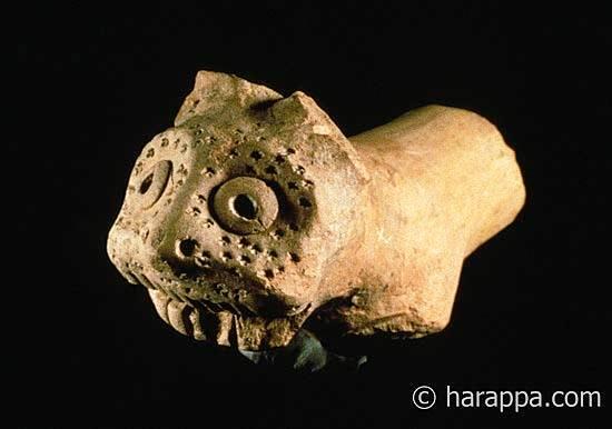 Tiger or leopard figurine with incised facial features, including punctated dots on the face that could be whisker marks. This figurine depicts a normal feline without horns or human face and therefore probably represents the actual wild animal. Hand formed with applique eyes. 