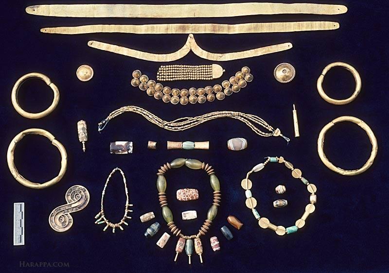 This collection of gold and agate ornaments includes objects found at both Mohenjo-daro and Harappa. At the top are fillets of hammered gold that would have been worn around the forehead.  The other ornaments include bangles, chokers, long pendant necklaces, rings, earrings, conical hair ornaments, and broaches. Such ornaments were never buried with the dead, but were passed on from one generation to the next. These ornaments were hidden under the floors in the homes of wealthy merchants or goldsmiths.