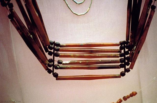  This artifact has 42 long bicone carnelian beads, 72 spherical bronze beads, 6 bronze spacer beads, 2 half moon shaped bronze terminals, 2 hollow cylindrical bronze terminals. Hoard No. 2, DK Area, Room 1, House 1, Trench E.