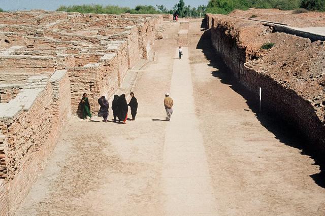 Looking north along First Street, Mohenjo-daro. "Only the facades of the eastern side of the street have been cleared, this being the limits decided upon for our excavations in this direction. Beyond this line, two-thirds of the mound, still remains untouched and will undoubtedly provide many buildings of interest for future excavations." (Mohenjo-daro, 1938, I, p. 25). The area to the left has been fully excavated and the area to the right is un-excavated. Later street levels are seen in the background.