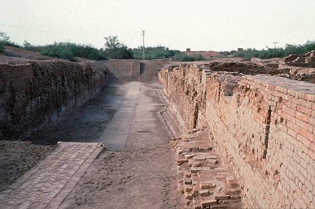 "In the Intermediate III Phase, FIrst Street was drained along the western side by a channel which may have been an open one. This drain, which averages 10 ins. wide by 1 ft. 11 ins. deep though well made was not very well aligned. It makes a bend where Block 6 enroaches on the street, and near the southern end of the section cleared it crossed the street and proceeded douthward on the opposite side." (Mohenjo-daro, 1938, I, p. 26).